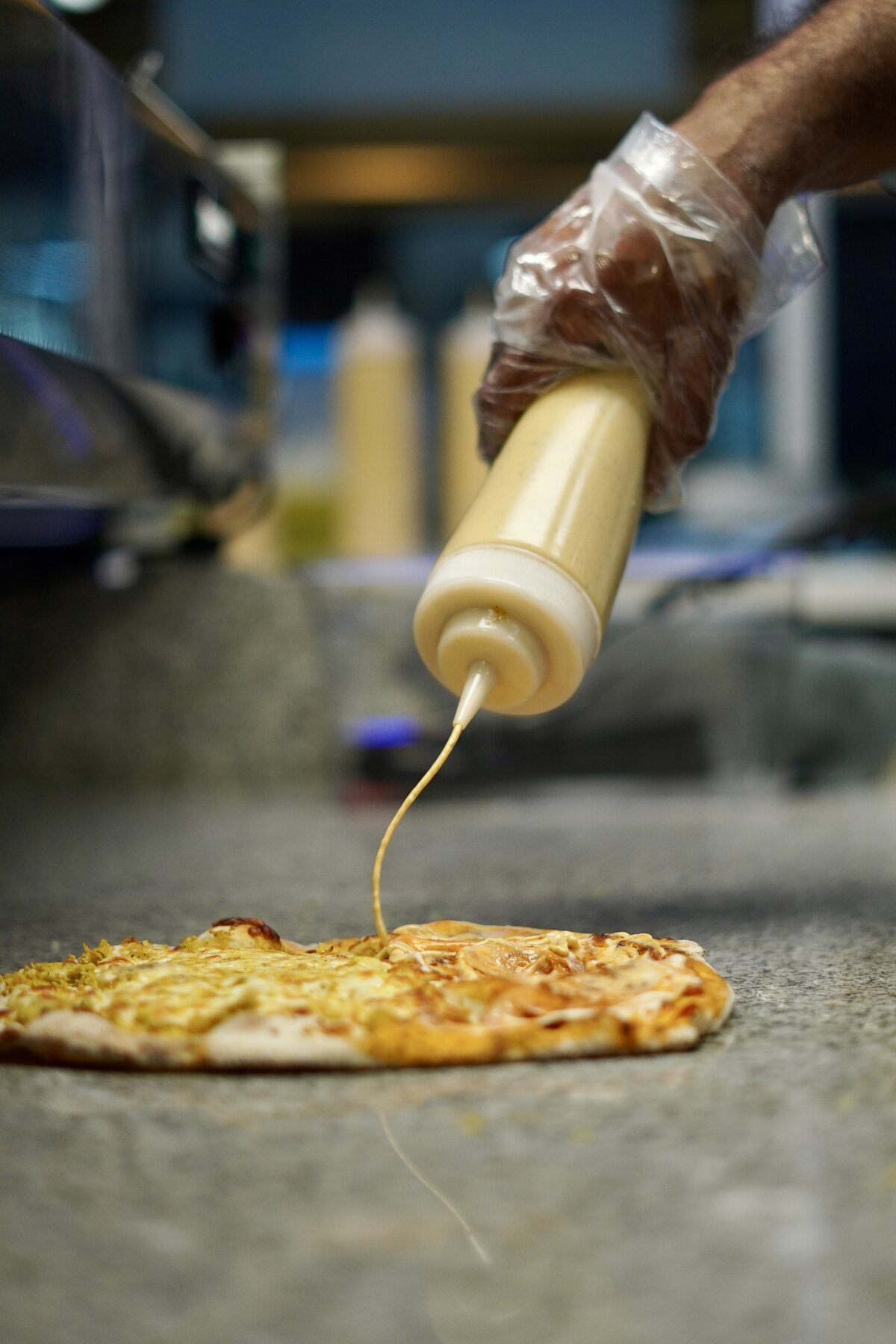 Sauce being added by hand to a freshly baked flatbread